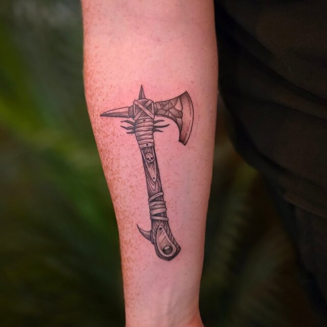 Etched battle axe with a wrapped handle, tattooed on a forearm