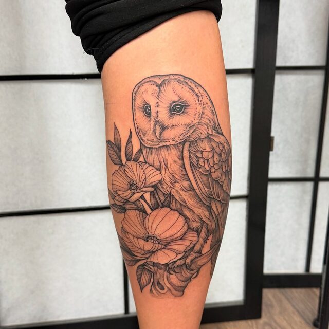 Barn owl among poppies with soft orange shading, tattooed on a calf