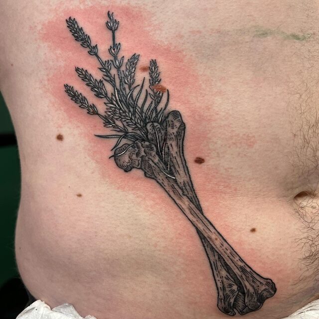 Etched tattoo of a long bone with a bunch of lavender tied to it