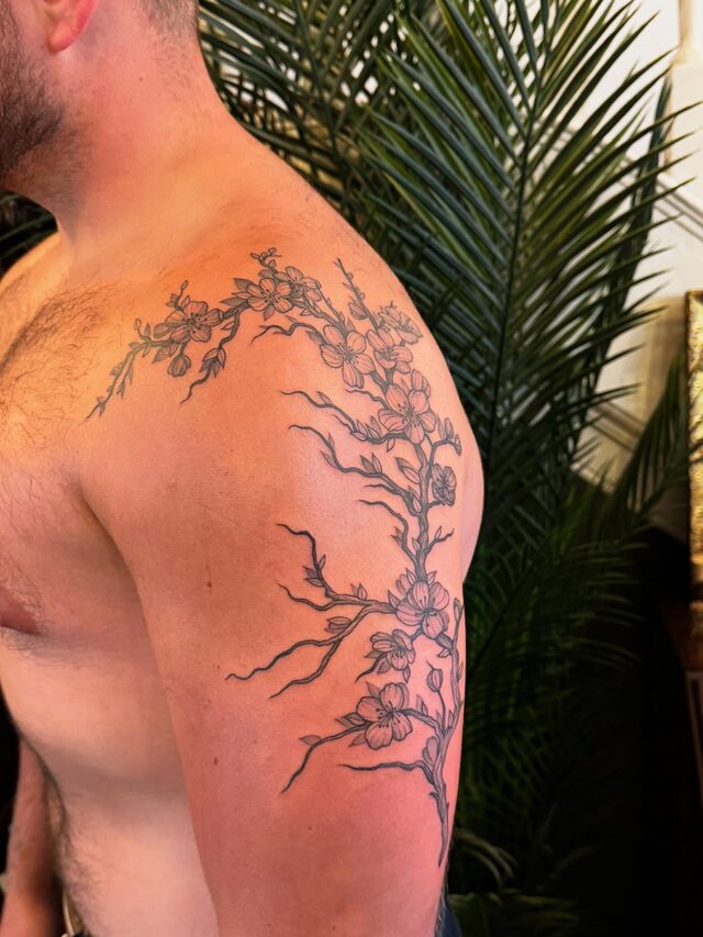 Cherry blossom branch climbing from the upper arm over the shoulder