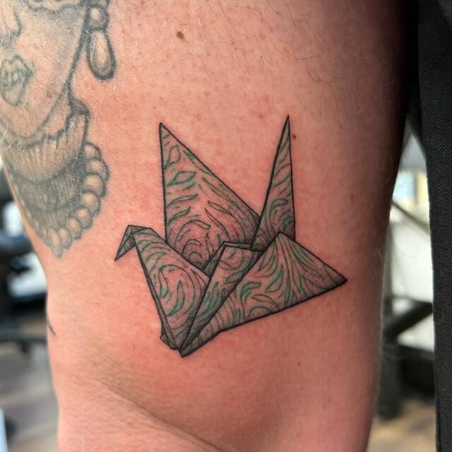 Tattoo of an origami paper crane with marbled patterning