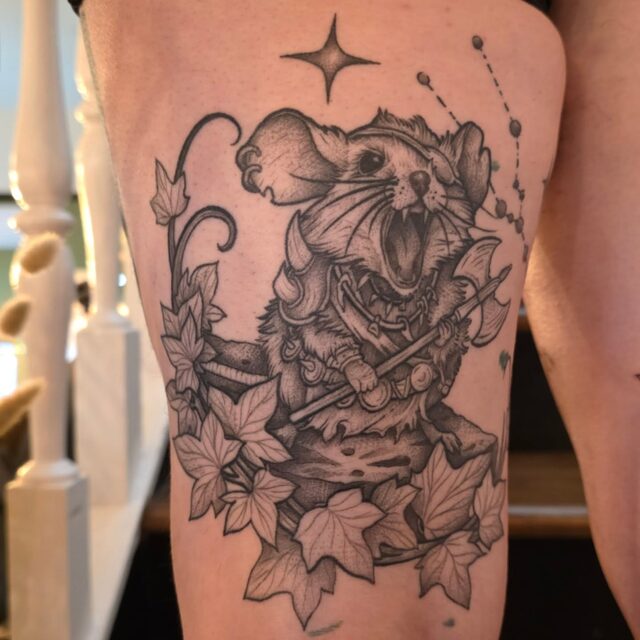 Etched rat holding a sword among ivy leaves beneath a star, tattooed on a thigh