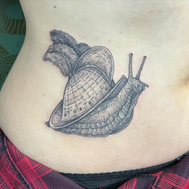 Etched tattoo of a snail with a plumed knight’s helmet for a shell, on the side of the hip
