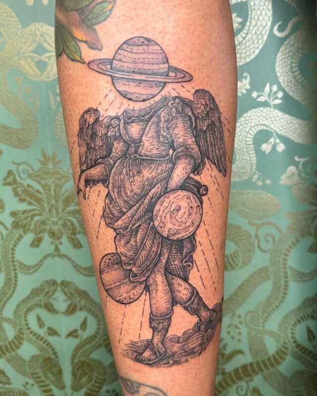 Etched tattoo of a winged angel in robes with the planet Saturn for a head, carrying planets, on a forearm