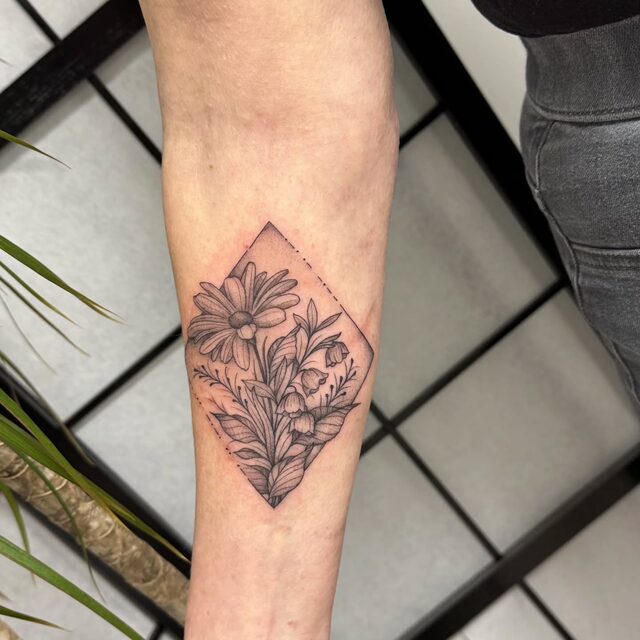 Wildflowers inside a diamond frame, tattooed on a forearm